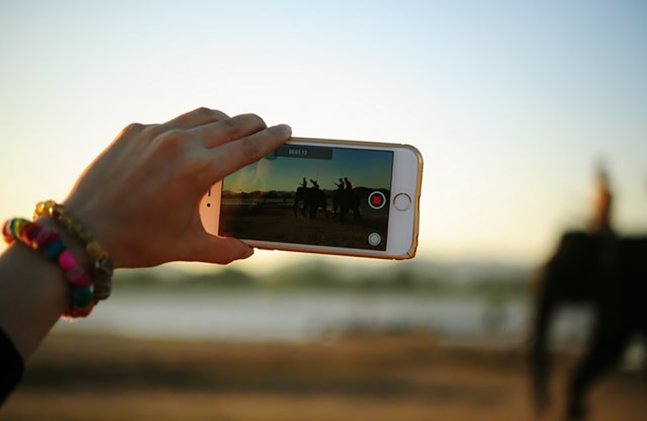 a woman holding an iphone and taking a video